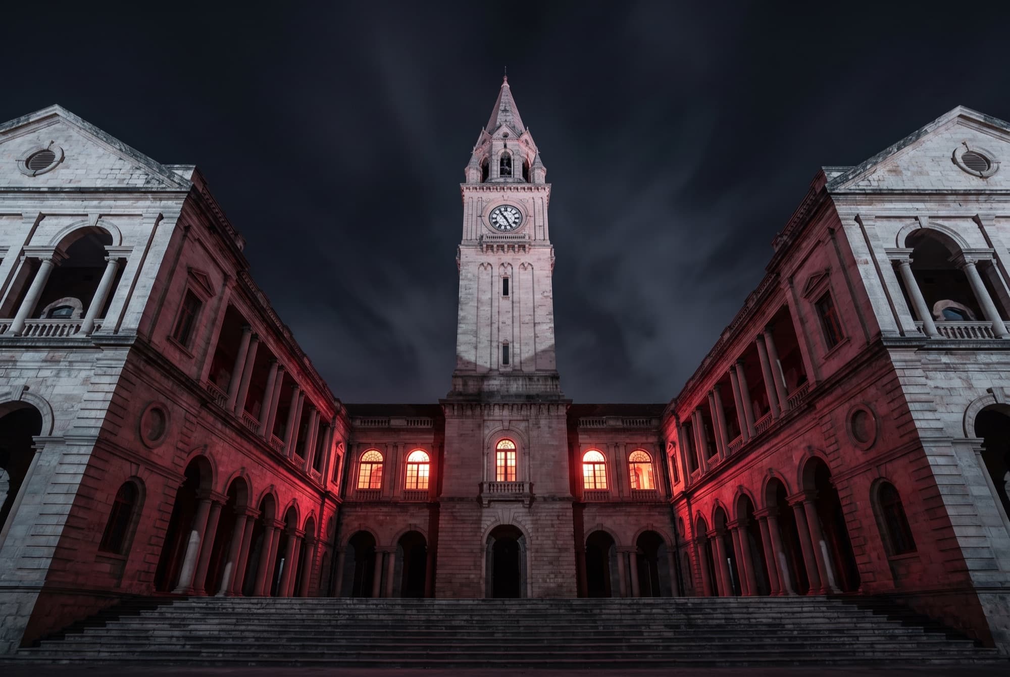 An Indian university building at night, lit in red